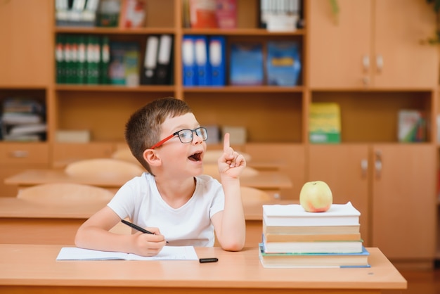교실 책상에 있는 초등학교 소년은 학업에 대한 새로운 아이디어를 찾으려고 합니다.