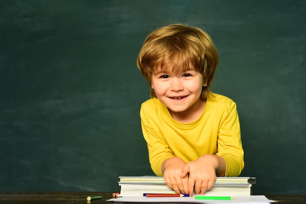 L'umore felice della scuola elementare sorride ampiamente a scuola il primo giorno di scuola il bambino sta imparando in classe il ...