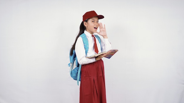 Bambina della scuola elementare che grida al lato isolato su fondo bianco