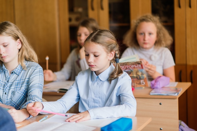 Elementary schoolchildren writing in books in the classroom