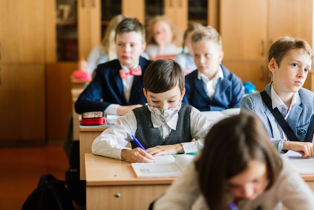 Elementary schoolchildren writing in books in the classroom