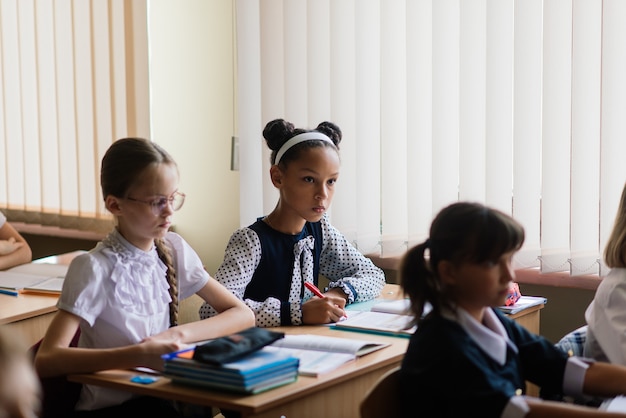 Elementary schoolchildren writing in books in the classroom