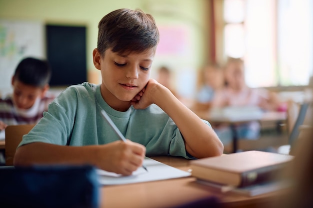 elementary student writing in notebook during a class at school