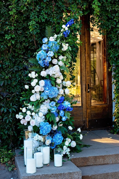 Elements of wedding decor, decorated with fresh white roses, blue orchids and candles. Wedding arch. Soft selective focus.