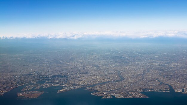 Elevate landscape of houses and roads at Fujinomiya city near the coast Wonderful top view from airplane window at day of winter season Plane flying above shore ocean Japan Fuji area