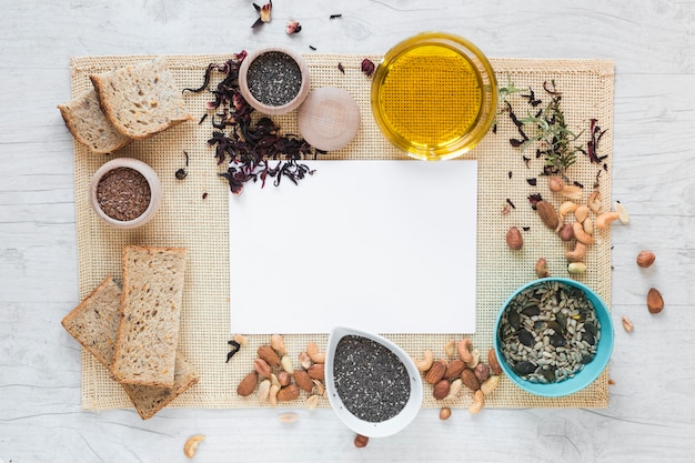 Photo elevated view of blank paper surrounded by healthy food over placemat on table