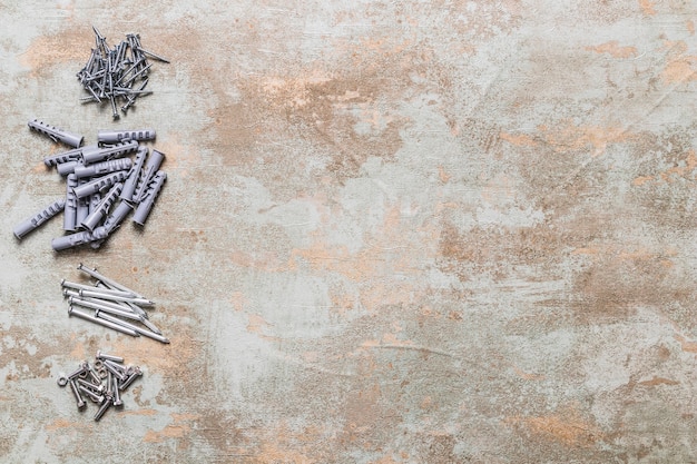 Photo elevated view of bolts, nails and wall plugs on old wooden background