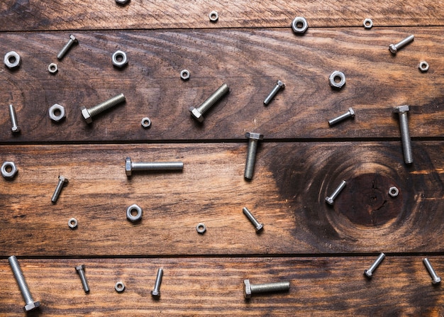 Elevated view of bolts and nuts on wooden background