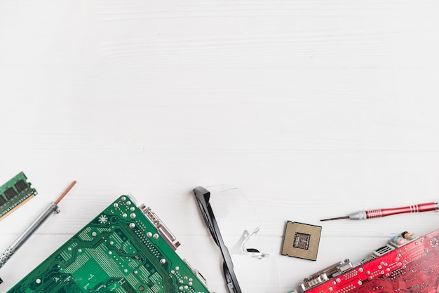 Elevated view of computer circuit boards and chip with tools on wooden background