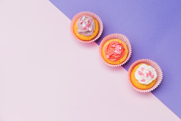 An elevated view of decorative cupcakes on the purple and pink dual background