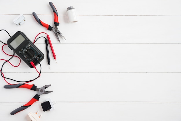 Foto vista elevata del multimetro digitale e delle attrezzature elettriche sullo scrittorio di legno bianco