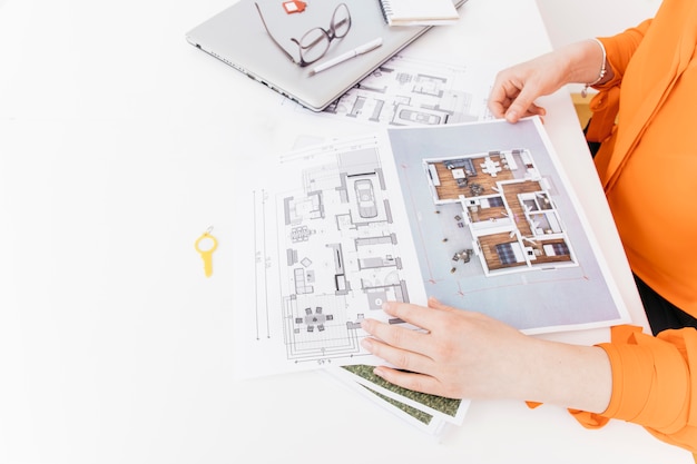 Elevated view of female hand holding blueprint on white desk