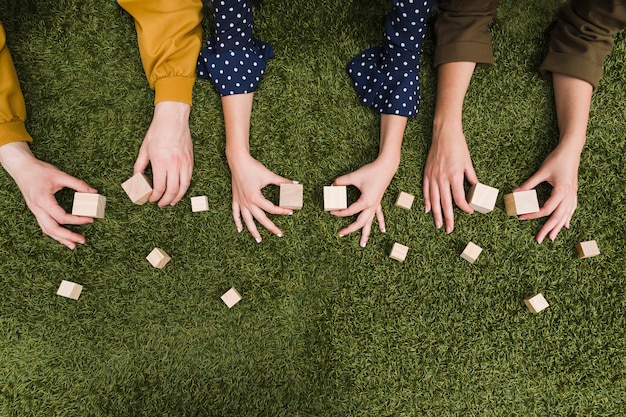 緑の草の上に手の空の木製ブロックを保持する上昇したビュー