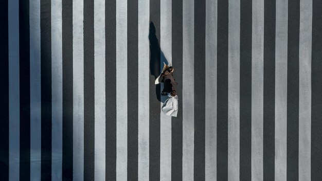 Elevated view over a japanese women pedestrian with shopping bags crossing a road intersection. Aerial of two asian friends going shopping in a scramble crosswalk.