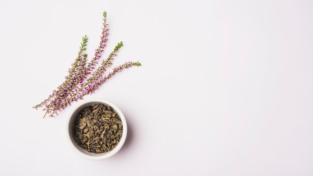 Elevated view of lavender flowers near dry petals in bowl on white surface