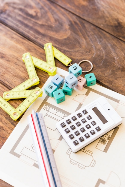 Elevated view of measure tape, ruler, calculator, math blocks and blueprint