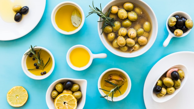 Photo elevated view of olive oil in different container on blue backdrop