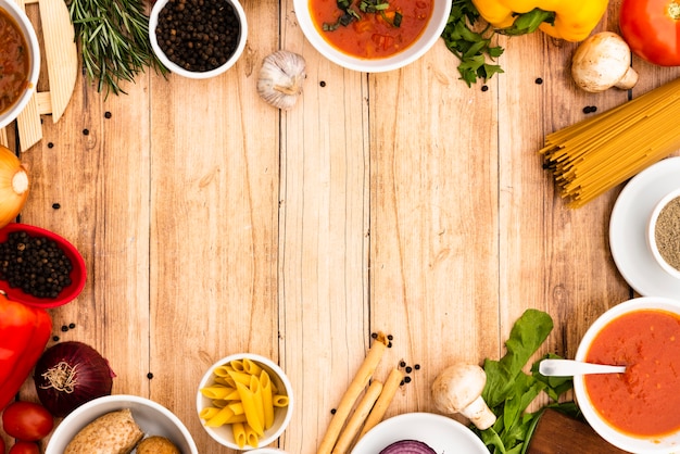 Elevated view of pasta ingredients arranged in frame on wooden surface