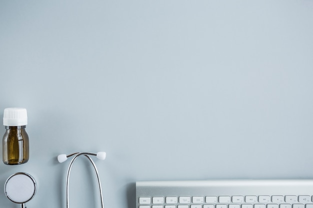 Photo elevated view of pills bottle, stethoscope and keyboard on desk