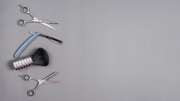Elevated view of scissors, shaving brush and razor over grey backdrop
