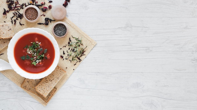 Elevated view of soup and ingredients on table cloth against wooden table