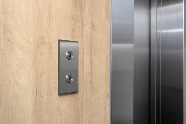 Elevator call buttons up and down on a wooden panel