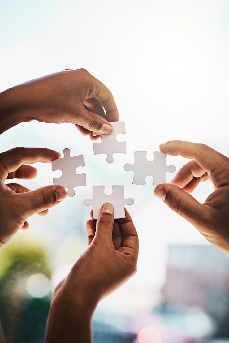 Foto elk probleem heeft een oplossing bijgesneden opname van zakenmensen die samen een puzzel voltooien in een modern kantoor