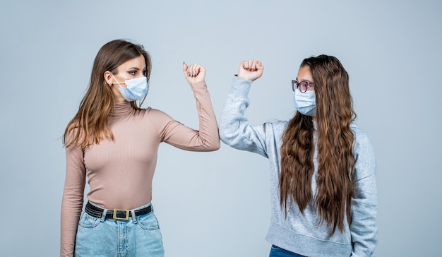 Elleboogbult. Vrienden met een beschermend medisch masker op zijn gezicht begroeten hun ellebogen in quarantaine.