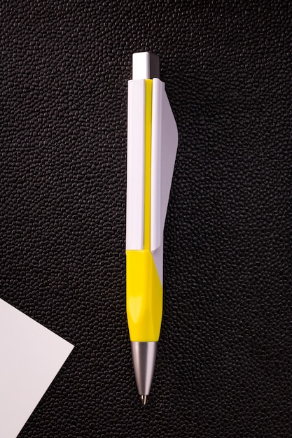 Ellow pen and white card on dark background.