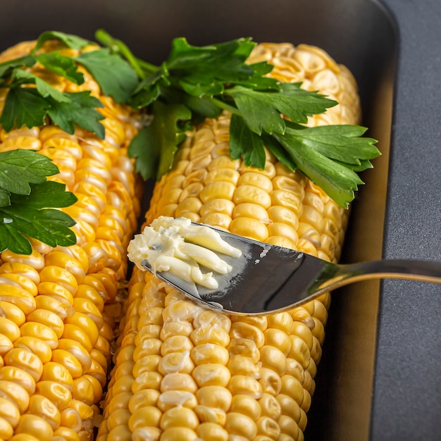 Elote Corn은 베이킹 시트에 치즈 또는 파마산 치즈, 고수, 향신료 및 칠리를 뿌립니다.