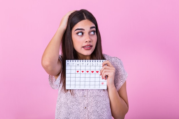 Embarrassed cute girl holding menstrual calendar