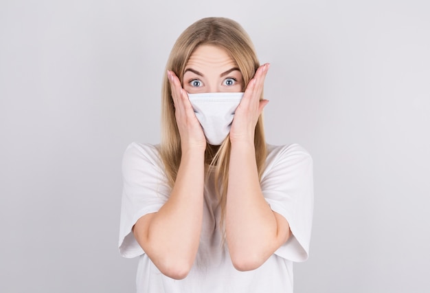 Embarrassed Young caucasian woman wearing medical mask standing over isolated white