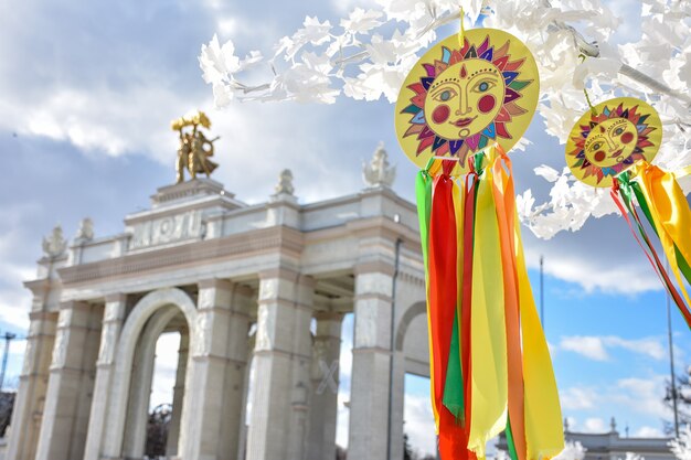 embleem van zon met kleurrijke linten op takken van witte boomveelkleurige linten tegen steen