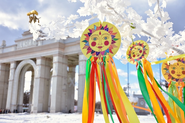 Emblema del sole con nastri colorati su rami di albero bianconastri multicolori contro la pietra