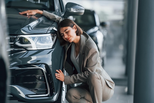 Photo embracing the car woman is indoors near brand new automobile indoors