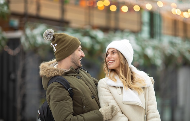 Embracing couple looking at camera with smiles in winter park.