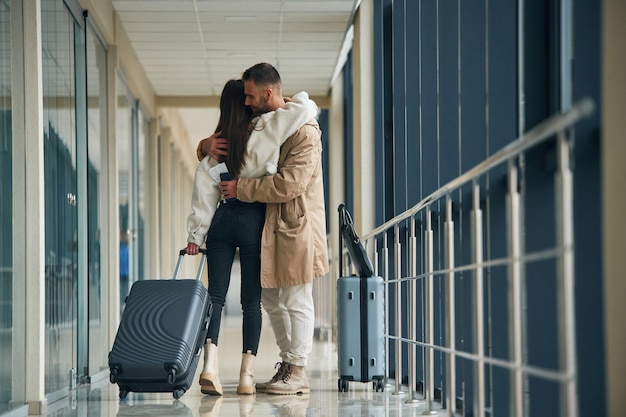 서로 포옹하는 커플이 공항 홀에 함께 있습니다.