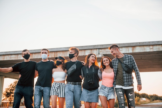 Foto abbracciarsi gruppo di giovani amici allegri che si divertono insieme festa all'aperto