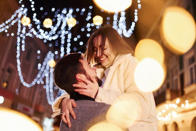 Photo embracing each other happy young couple celebrating new year outdoors on the street