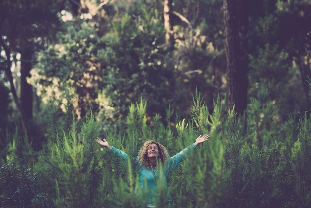 Abbracciando il concetto di natura all'aperto e amore con una bella donna felice nel mezzo di un bosco di alberi forestali in totale felicità e gioia