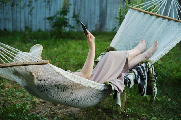 Embracing slow living woman finds solitude in backyard hammock smartphone in hand for a mindful