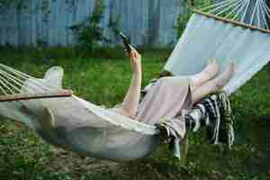 Photo embracing slow living woman finds solitude in backyard hammock smartphone in hand for a mindful