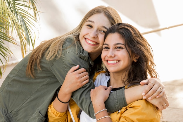 Photo embracing young female friends looking at camera