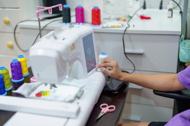 刺繡手工芸品趣味SMEビジネスファミリービジネスアジアの女性デザイナーの肖像画は、顧客の注文に応じて自動刺繡機を使用してパターンをデザインしています