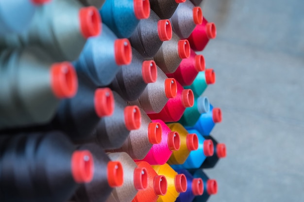 Photo embroidery thread spool using in garment industry, row of multicoloured yarn rolls