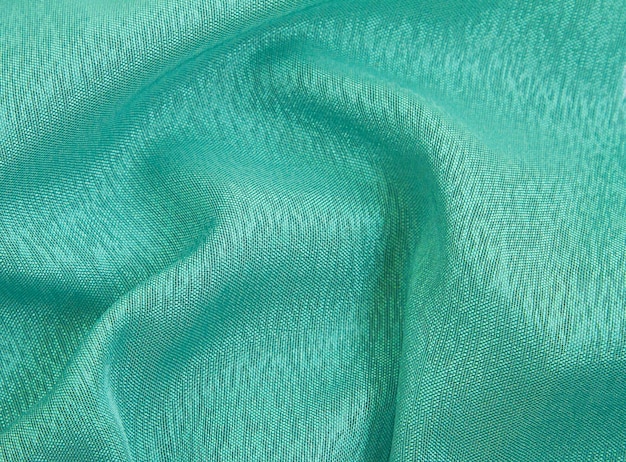 Emerald color crumpled fabric background,light airy, transparent fabric texture.