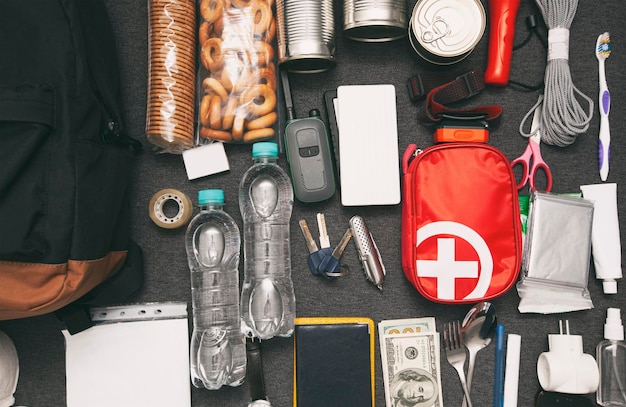 Emergency backpack equipment organized on the table Documents waterfood first aid kit and another items needed to survive