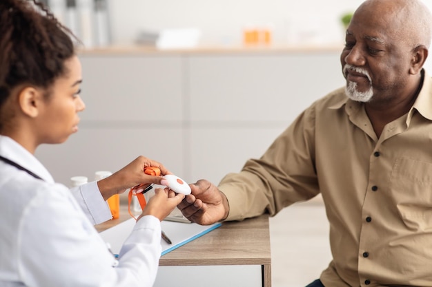 Emergency call system doctor giving alarm button to senior man