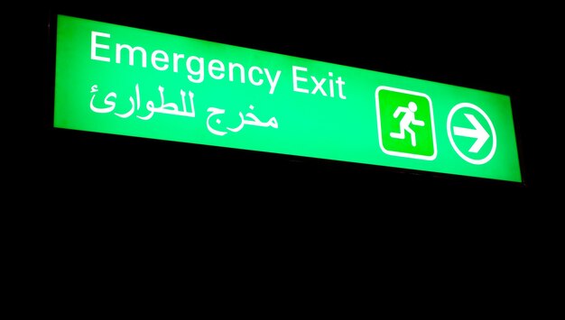 Photo emergency exit sign in an international airport in middle east with arabic information