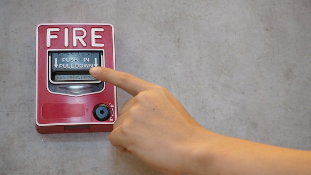 Foto emergenza di allarme antincendio o allarme o attrezzatura di avvertimento campana in colore rosso con la mano nell'edificio per la sicurezza.